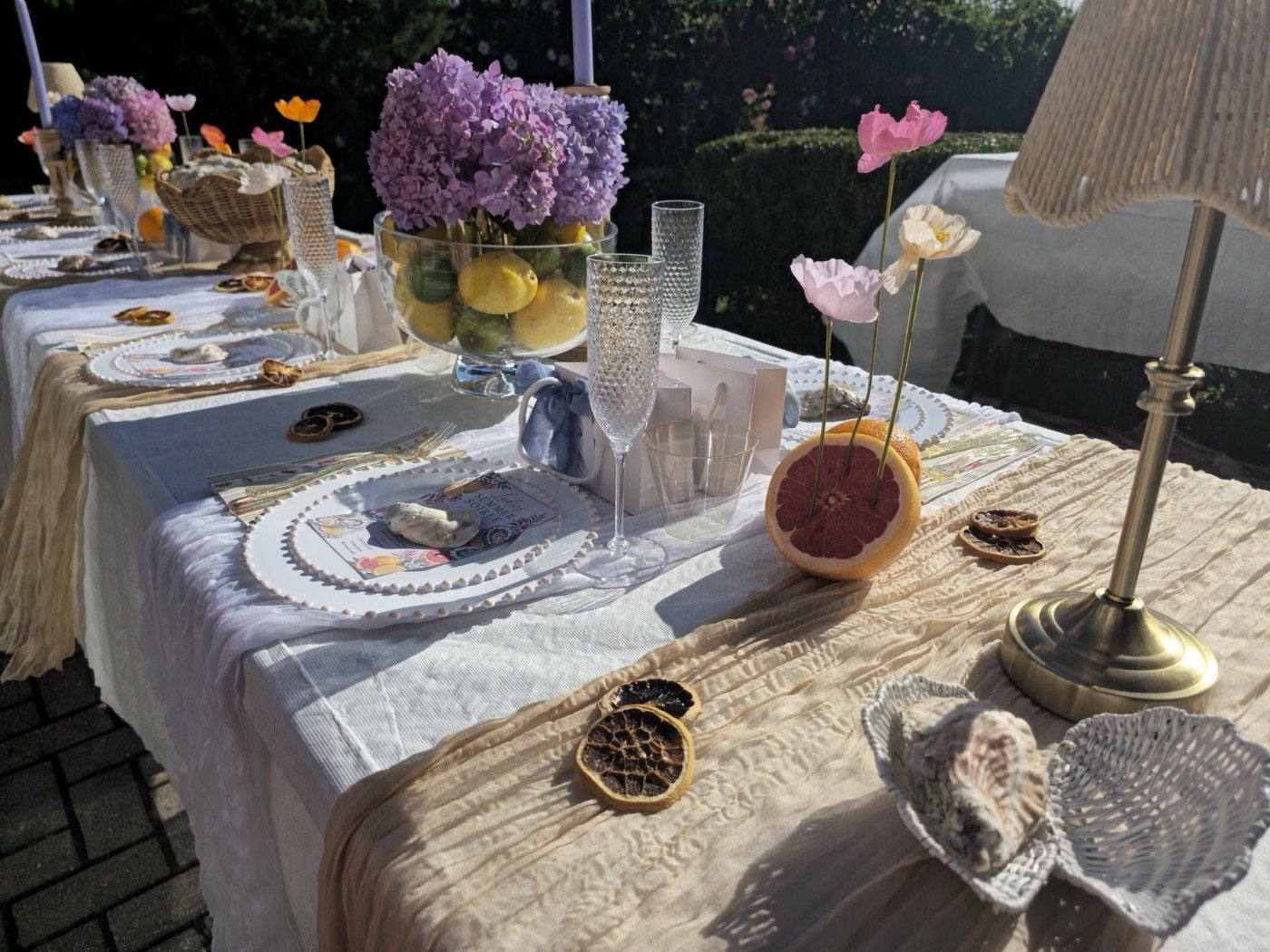 Place setting with pearl-beaded charger, soirée menu, hydrangea and lemon centerpiece and paper poppies in a grapefruit